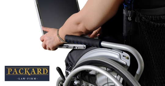 closeup photo of a person on a wheelchair holding a laptop